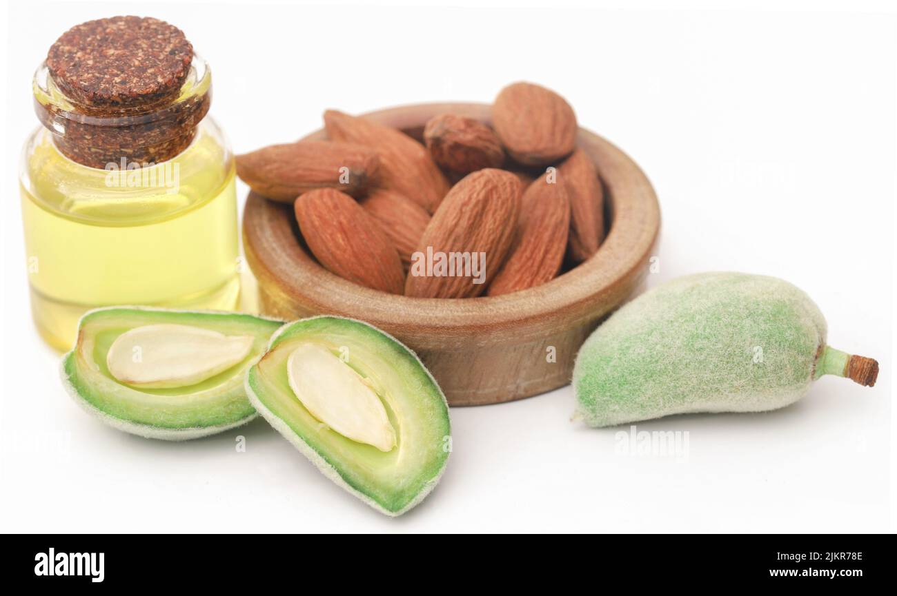 Mandorla verde e pelata e olio essenziale su sfondo bianco Foto Stock