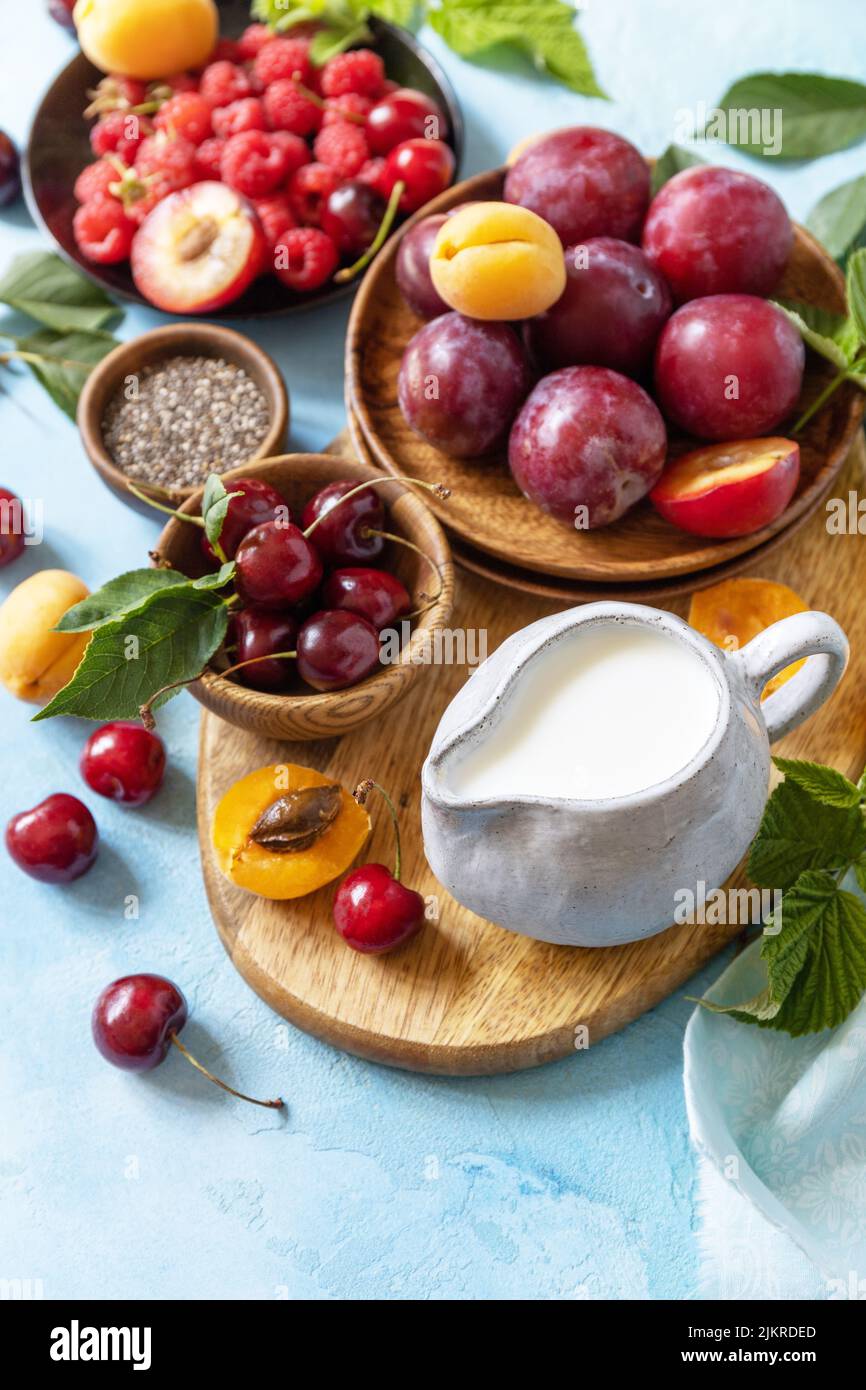 Ingredienti per un frullato sano. Latte e frutti di bosco (lampone, ciliegia, prugna, albicocca) su un tavolo in pietra. Alimentazione sana, alimentazione cruda e vegan f Foto Stock