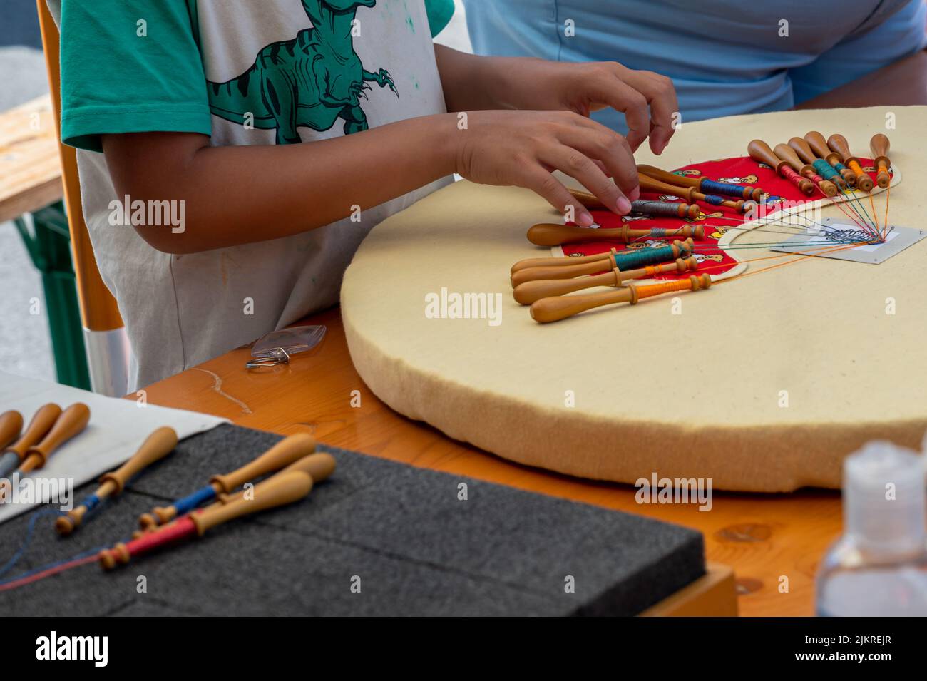Mani di bambino che fanno merletto della bobina. Fili colorati di pizzo. Abilità e creatività. Foto Stock