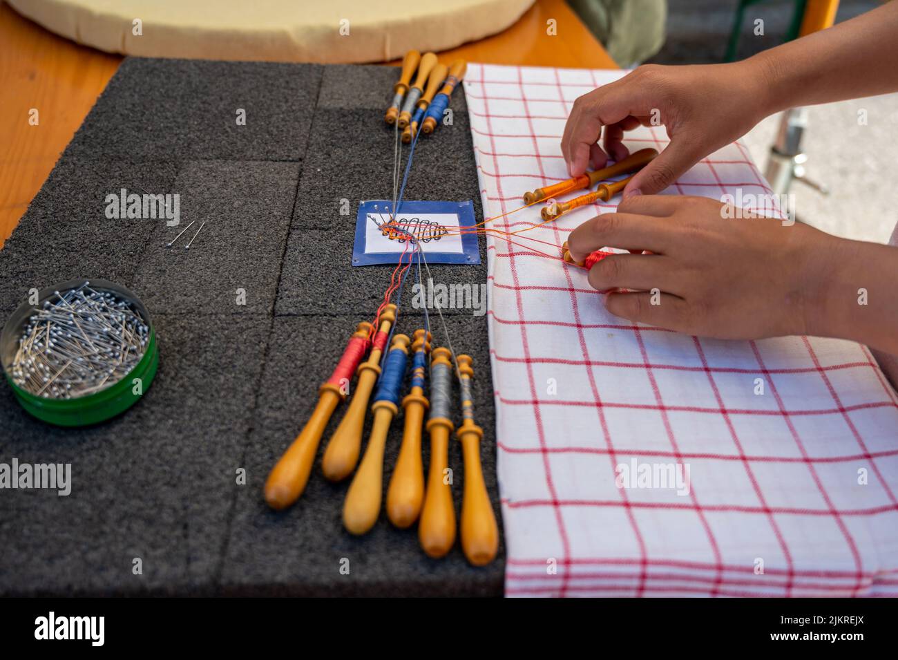 Mani di bambino che fanno merletto della bobina. Fili colorati di pizzo. Abilità e creatività. Foto Stock