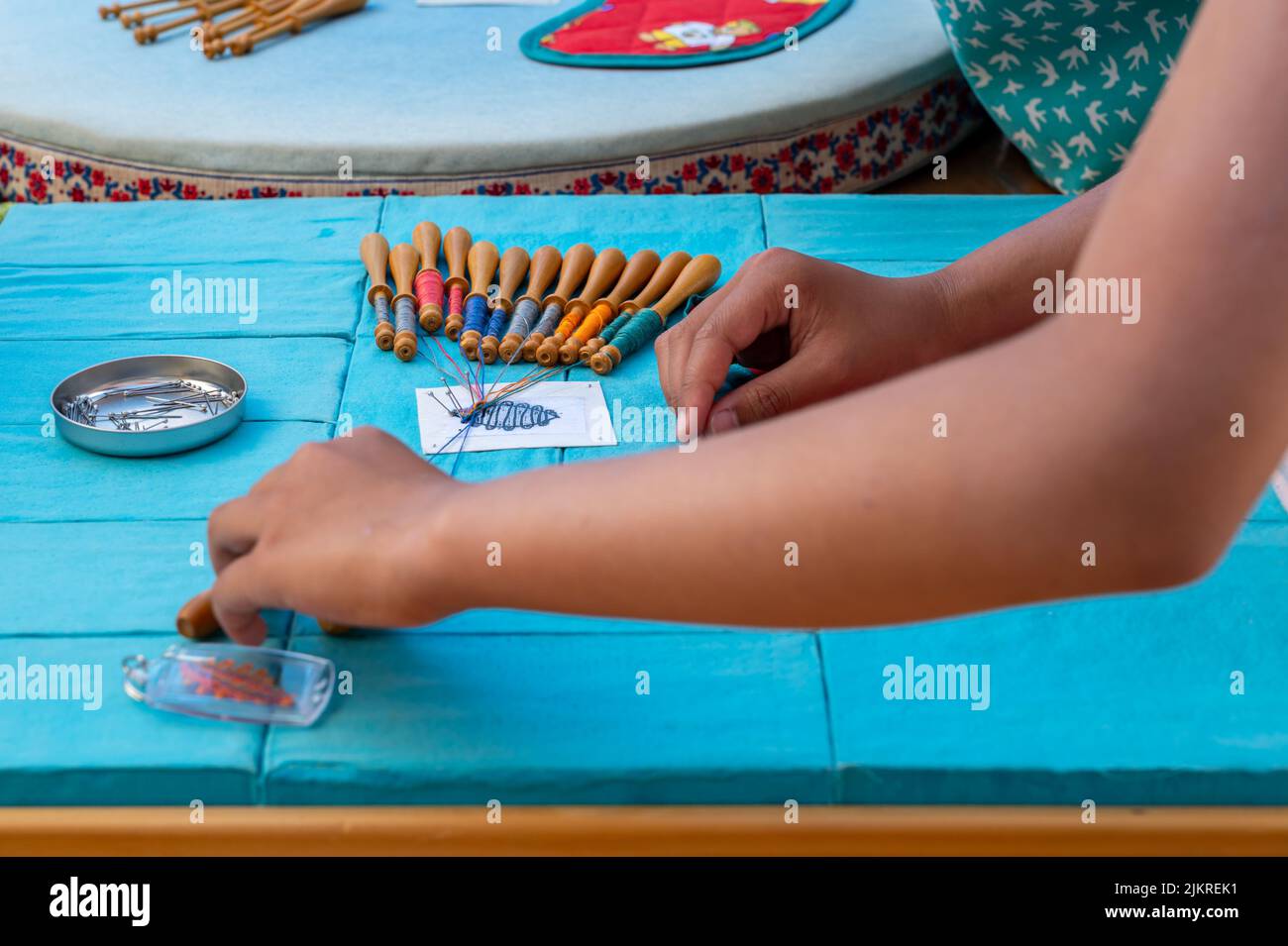 Mani di bambino che fanno merletto della bobina. Fili colorati di pizzo. Abilità e creatività. Foto Stock