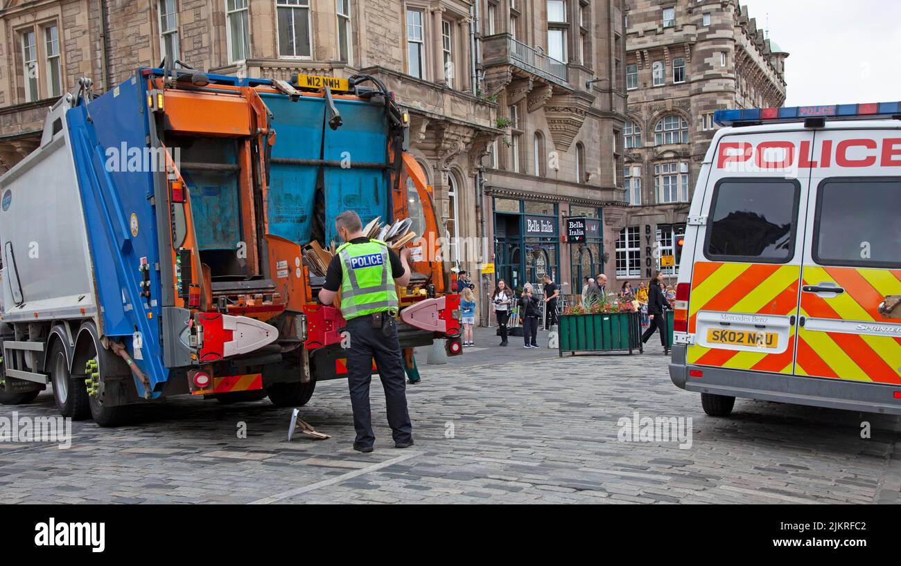 Centro citta', Edimburgo, Scozia, Regno Unito. 3rd ago 2022. Nuvoloso mattinata noiosa nel centro della città per i residenti e i turisti, Royal Mile era occupato con escursioni a piedi e alcuni gruppi che hanno consegnato volantini per gli spettacoli di EdFringe. Nell'immagine: Al di là della chiamata di dovere, un funzionario di voce molto utile assiste un raccoglitore di rifiuti per caricare i rifiuti sul carrello come il traffico stava cominciando a sostenere nel Royal Mile. Credit: ArchWhite/alamy Live news Foto Stock