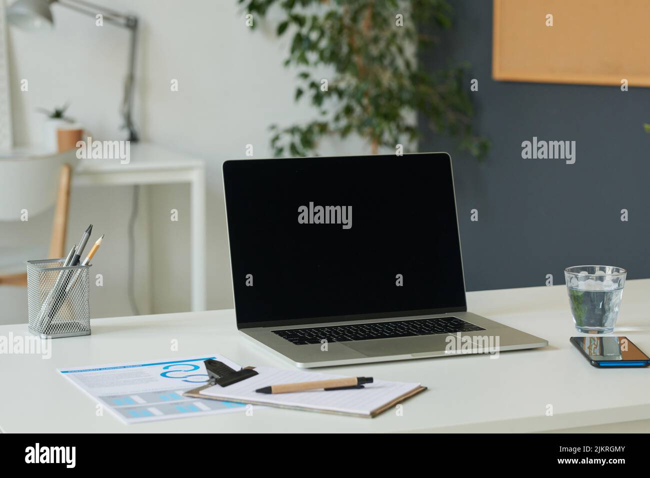 Primo piano di laptop e documenti sulla scrivania di un ufficio moderno Foto Stock