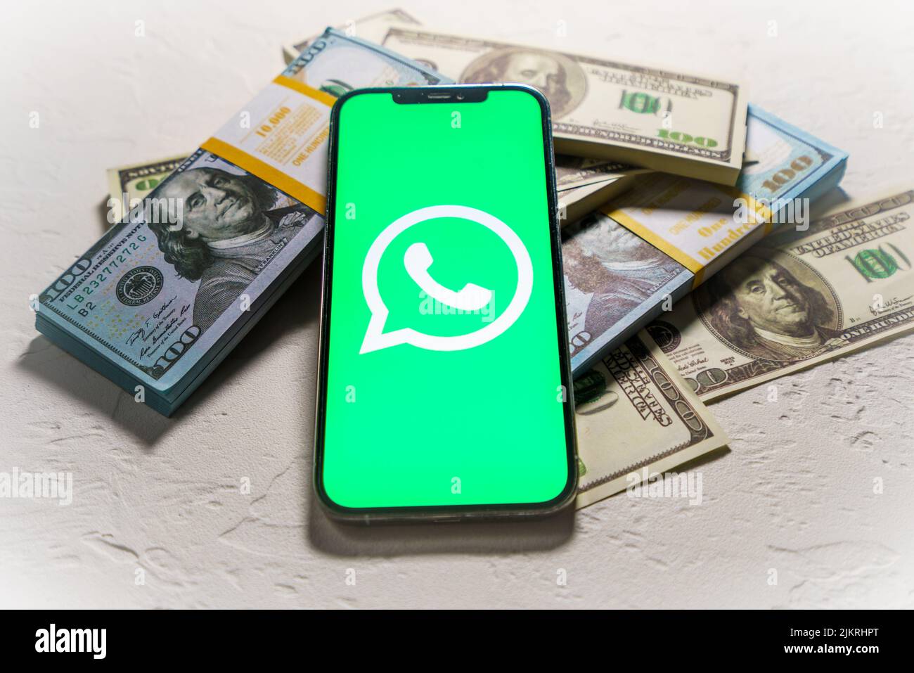 Berlino, Germania - 02 febbraio 2022: Apple iPhone 12 Pro con Messenger WhatsApp sullo schermo e denaro in dollari Foto Stock