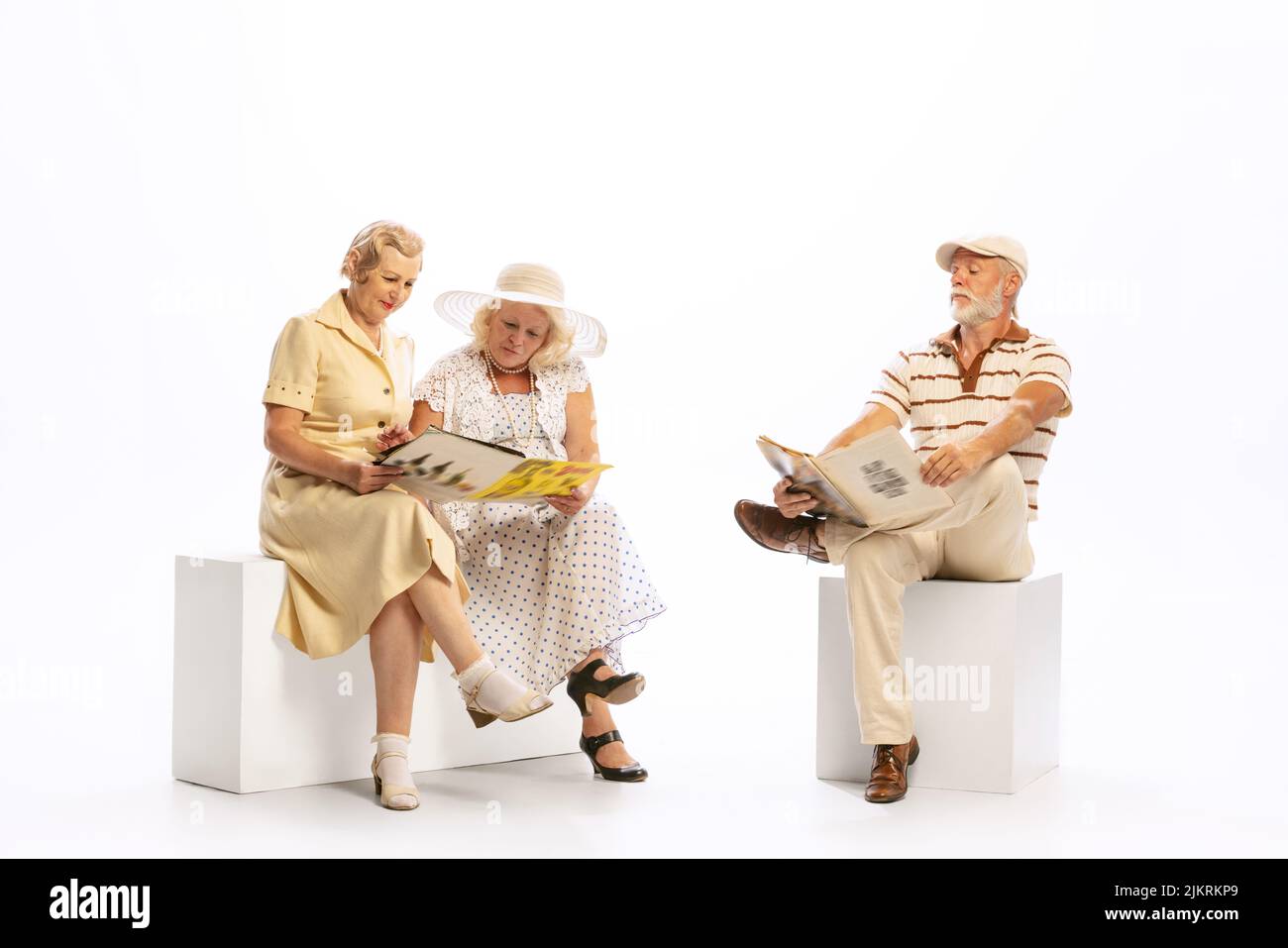 Bell'uomo anziano e due donne affascinanti in abiti vintage stile retrò isolato su sfondo bianco. Concetto di 60s, 70s, stile di moda americano Foto Stock