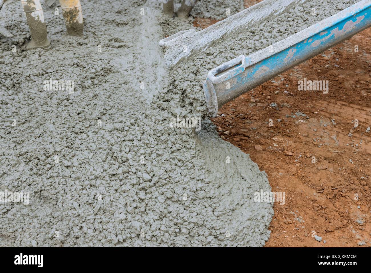 Versare calcestruzzo bagnato durante la pavimentazione di un vialetto in cantiere Foto Stock