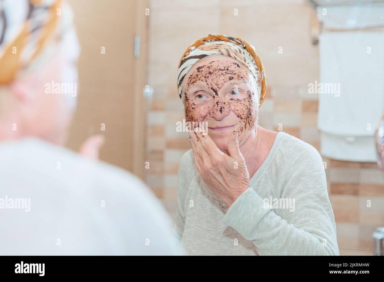 Donna anziana che si prende cura del suo volto Foto Stock