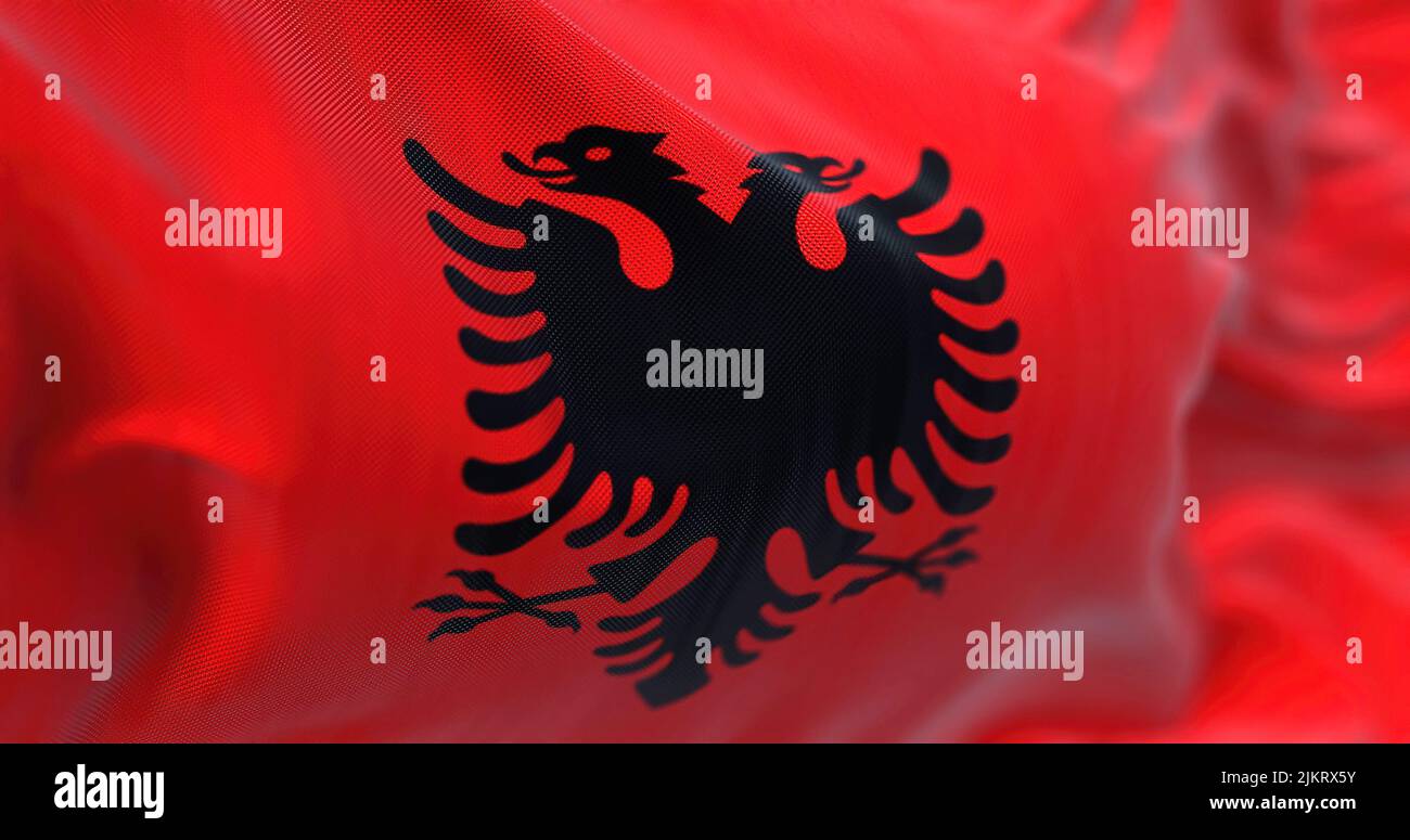 Vista ravvicinata della bandiera nazionale albanese che sventola nel vento. L'Albania è un paese dell'Europa sudorientale. Tessuto testurizzato sfondo. Selettivo foc Foto Stock