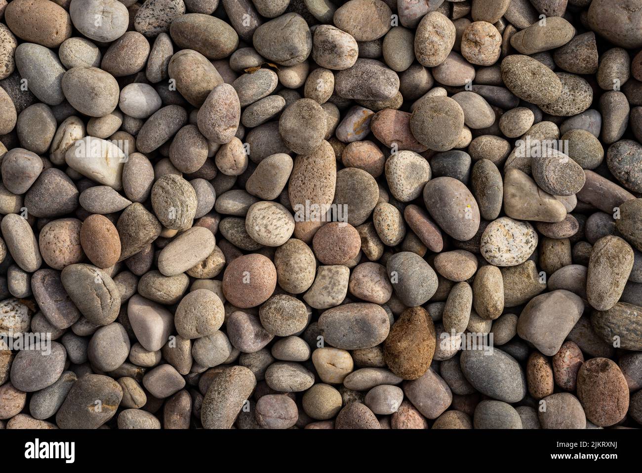 Sfondo astratto di pietre rotonde naturali irregolari ruvide ruvide marrone e beige ciottoli. Foto Stock