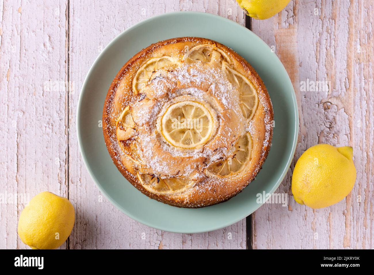 Torta di limone vegana fresca fatta in casa servita su un piatto color menta su un tavolo bianco rustico in legno. Dolce dessert con agrumi come un piacere rinfrescante. Foto Stock