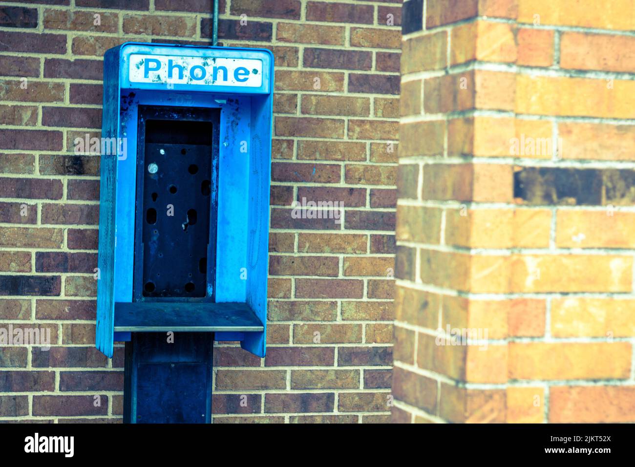 Telefono a pagamento abbandonato vuoto contro muro di mattoni Foto Stock