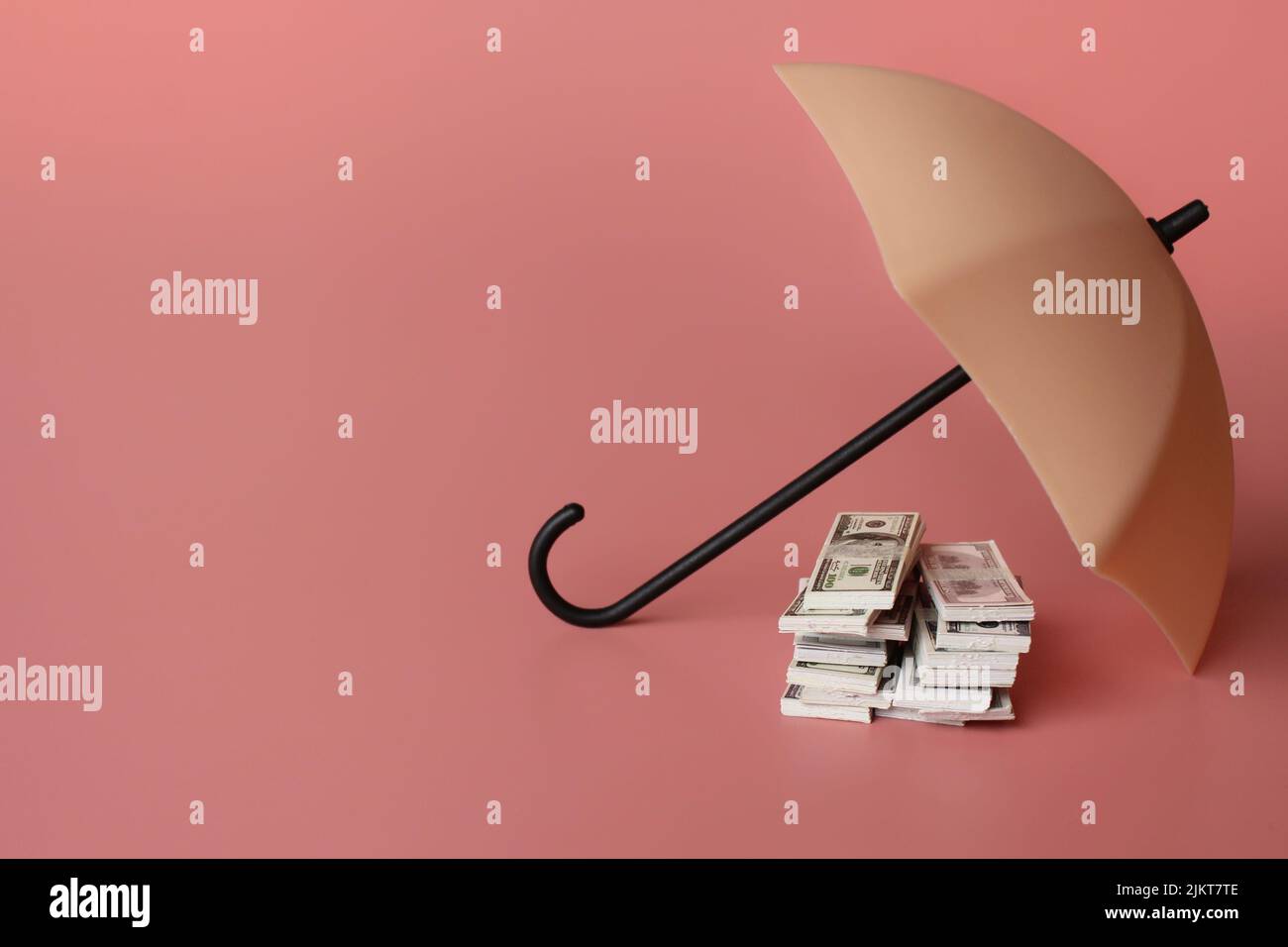 Pila di denaro e ombrello per la protezione con spazio per la copia. Sicurezza finanziaria e concetto di investimento. Foto Stock