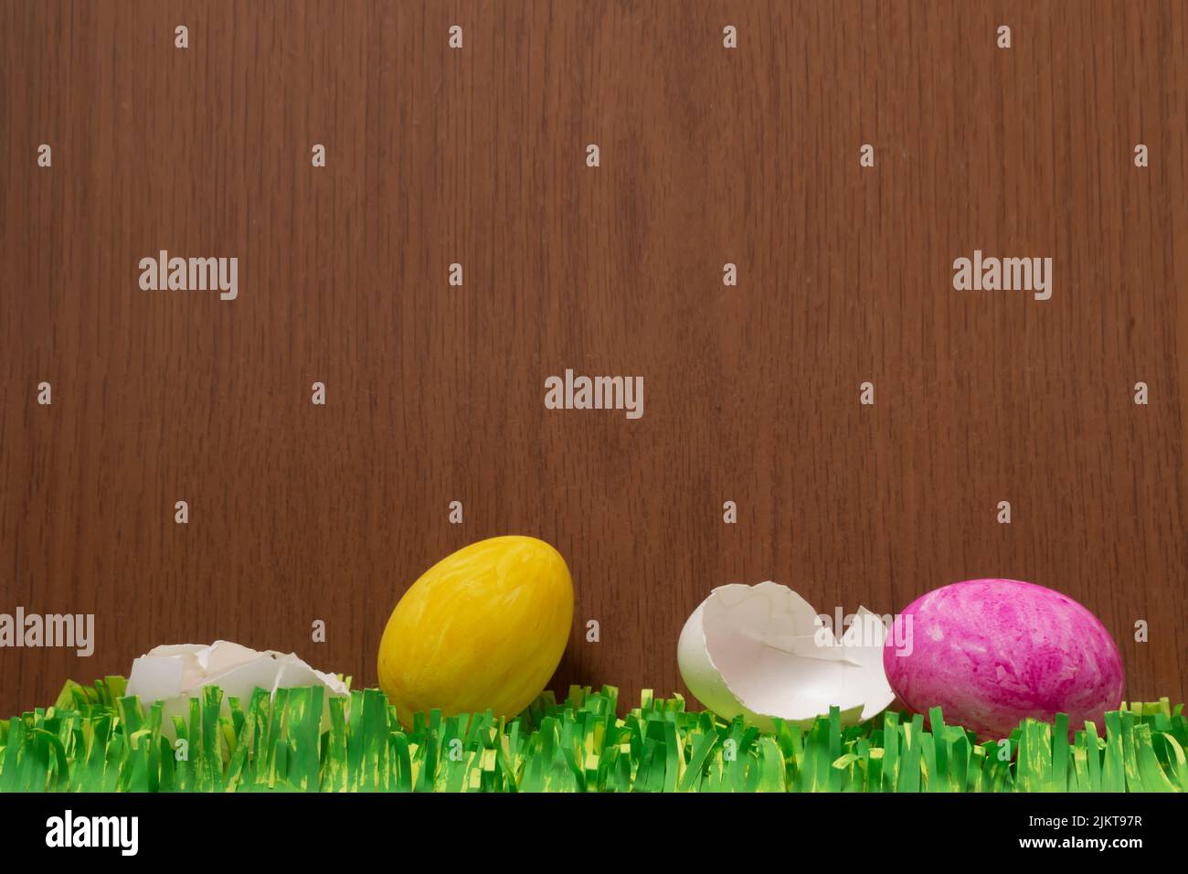 Un colpo verticale di uova di Pasqua rotte con erbe di carta su una superficie di legno marrone Foto Stock
