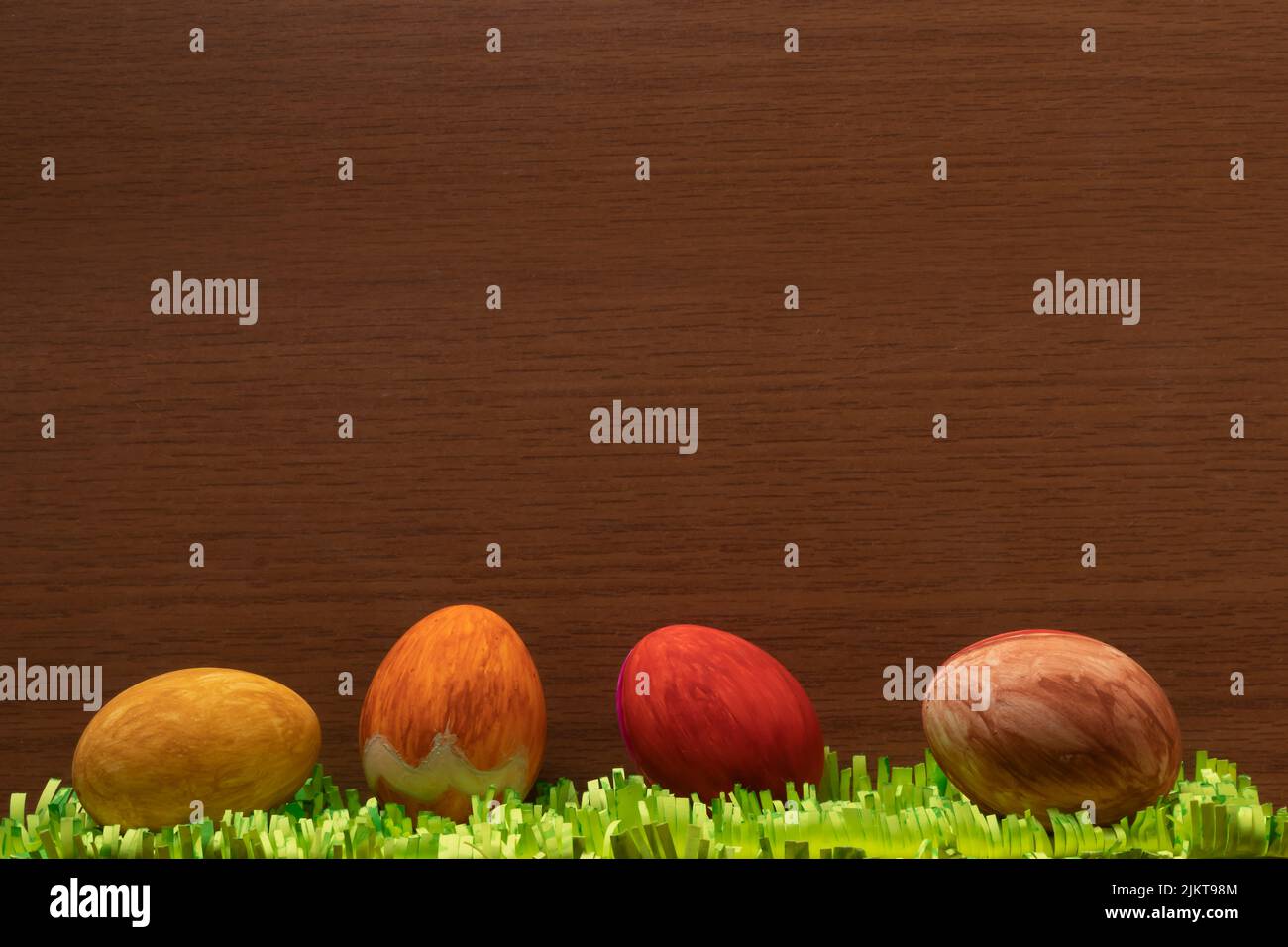 Un primo piano di uova di Pasqua con erbe di carta su una superficie di legno marrone Foto Stock