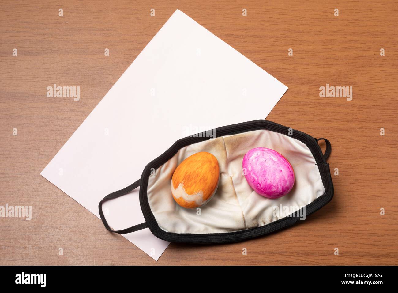 Un primo piano di uova di Pasqua su un facemask e carta bianca su un tavolo Foto Stock