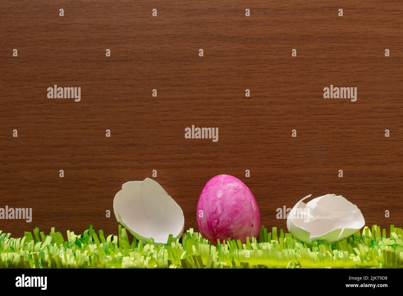 Un primo piano di uova di Pasqua rotte con erbe di carta su una superficie di legno marrone Foto Stock