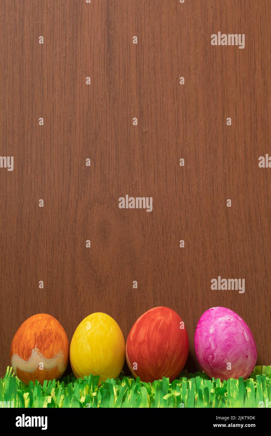 Un colpo verticale di uova di Pasqua con erbe di carta su una superficie di legno marrone Foto Stock