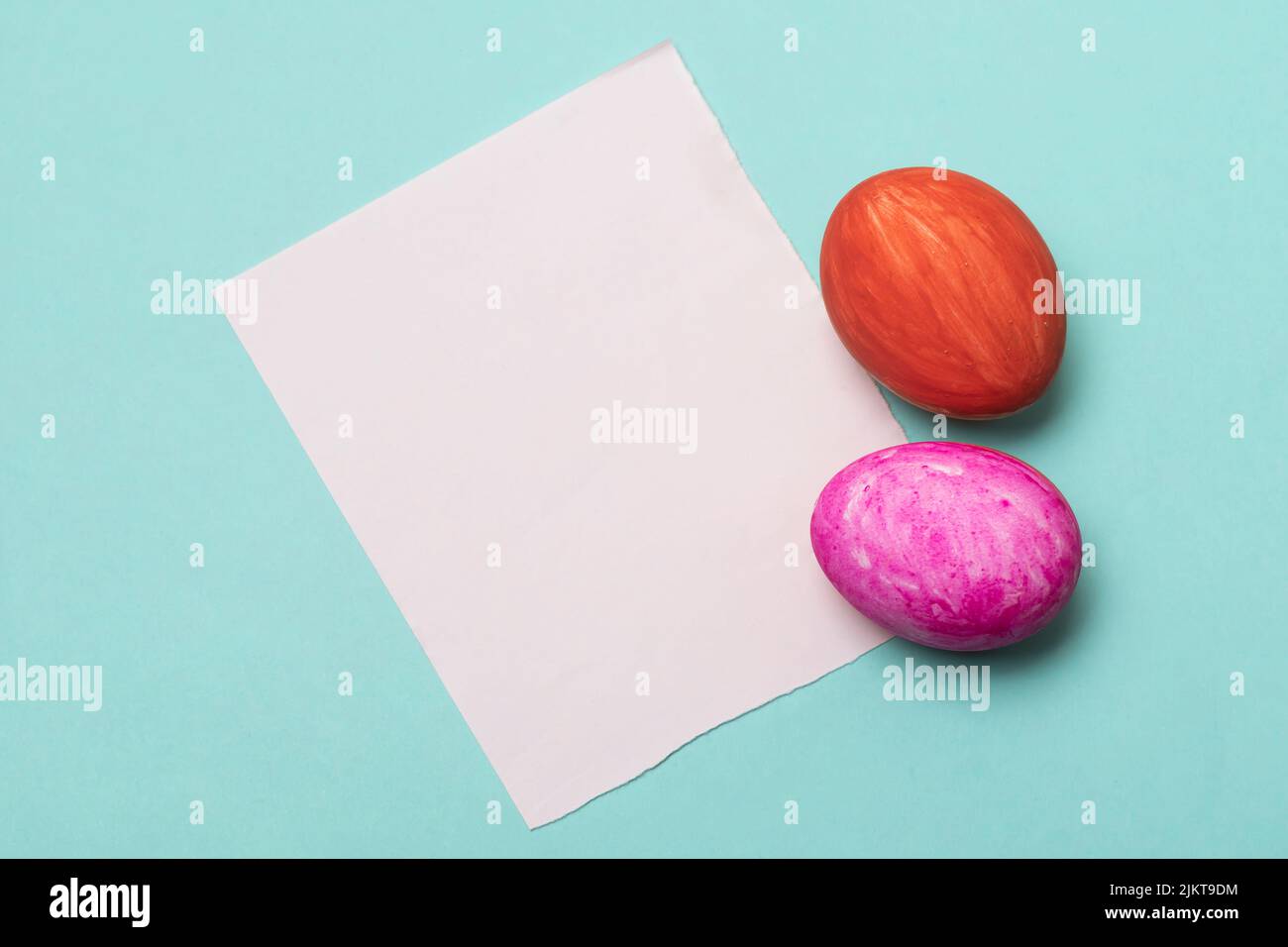 Un primo piano di uova di Pasqua con carta bianca isolato su sfondo azzurro con spazio di copia Foto Stock