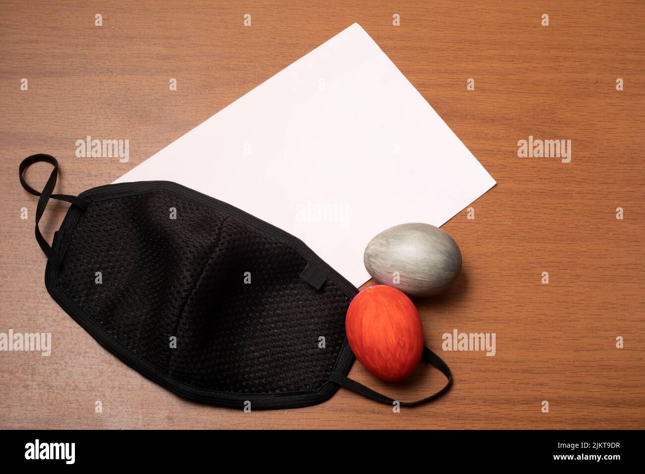 Un primo piano di uova di Pasqua su un facemask e carta bianca su un tavolo Foto Stock