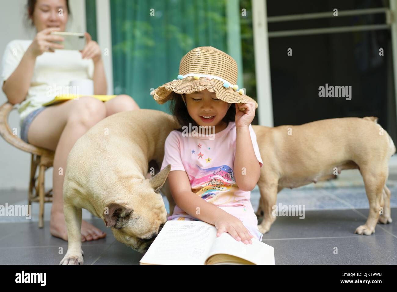 Un bambino del sud-est asiatico carino con i suoi cani con sfondo sfocato di sua madre fotografando Foto Stock
