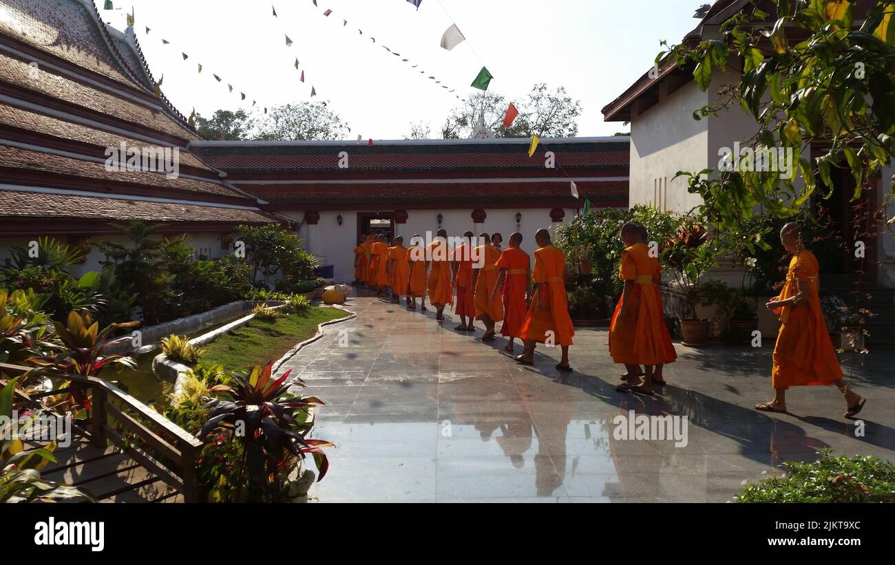 I monaci che camminano in una coda nel cortile del tempio di Phitsanulok nel nord della Thailandia Foto Stock