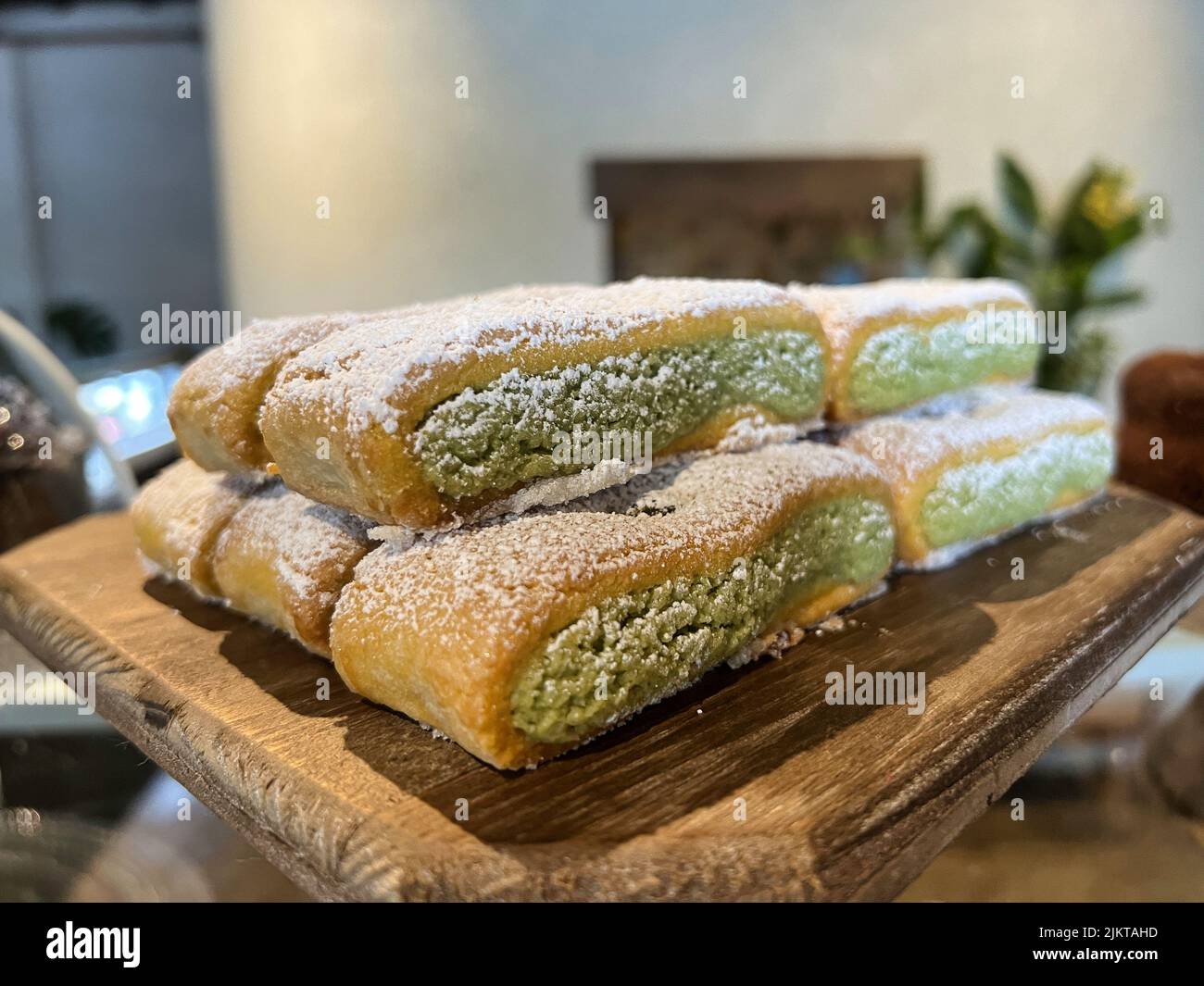 Un primo piano di piccole torte con crema verde su un piedistallo di legno Foto Stock