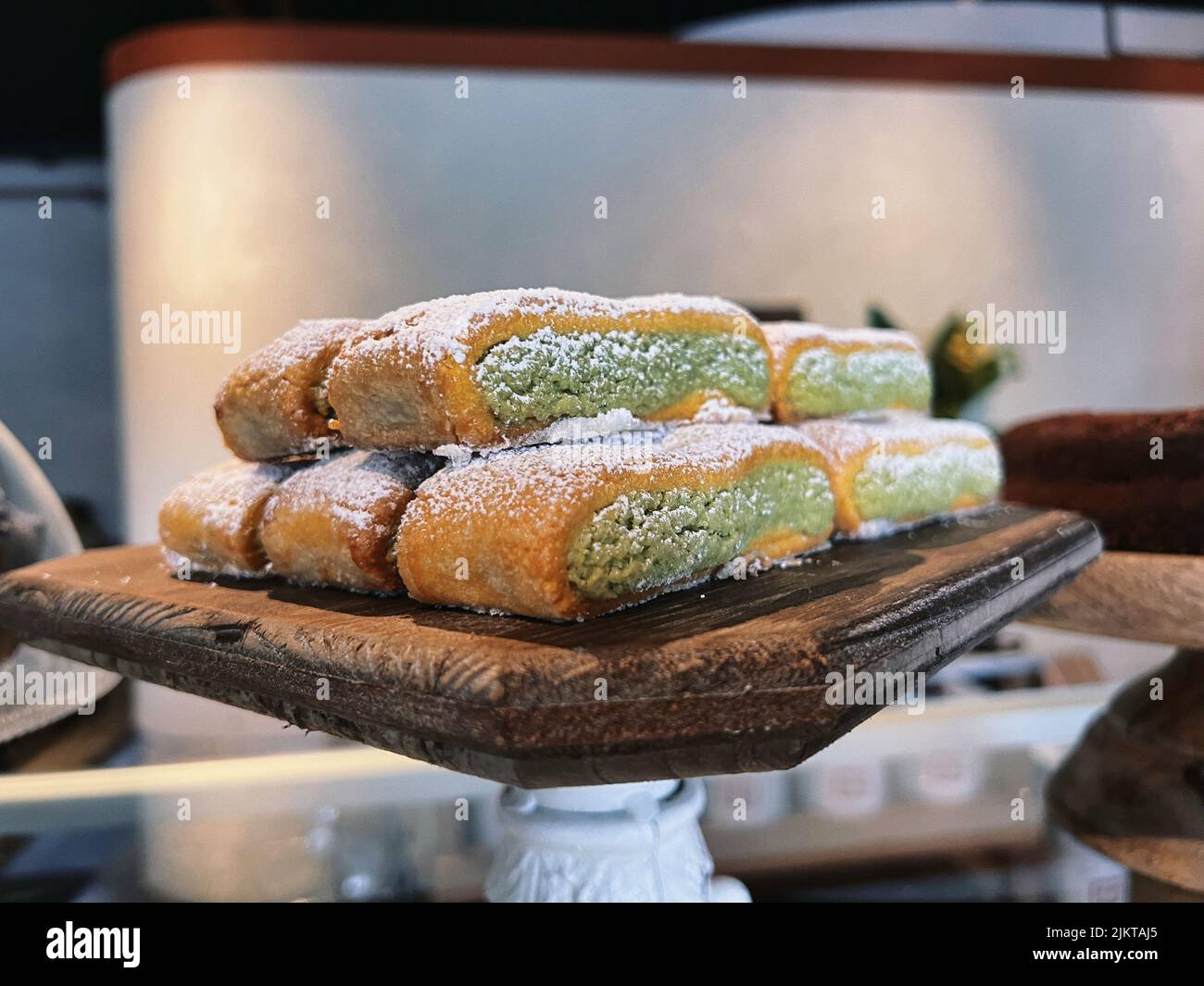 Un primo piano di piccole torte con crema verde su un piedistallo di legno Foto Stock
