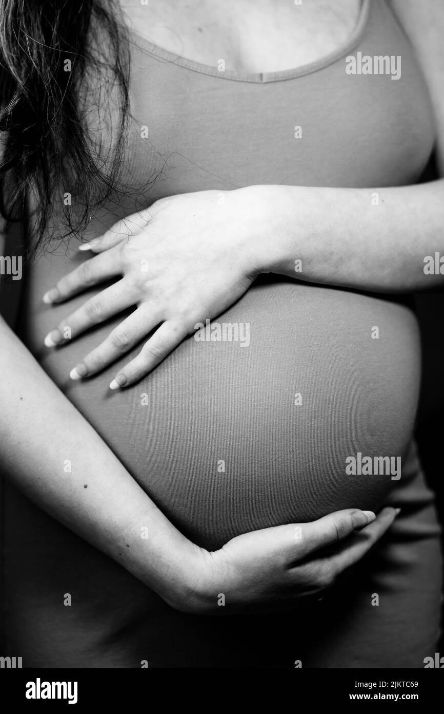 Donna incinta che tiene il suo ventre. 27 settimane Foto Stock