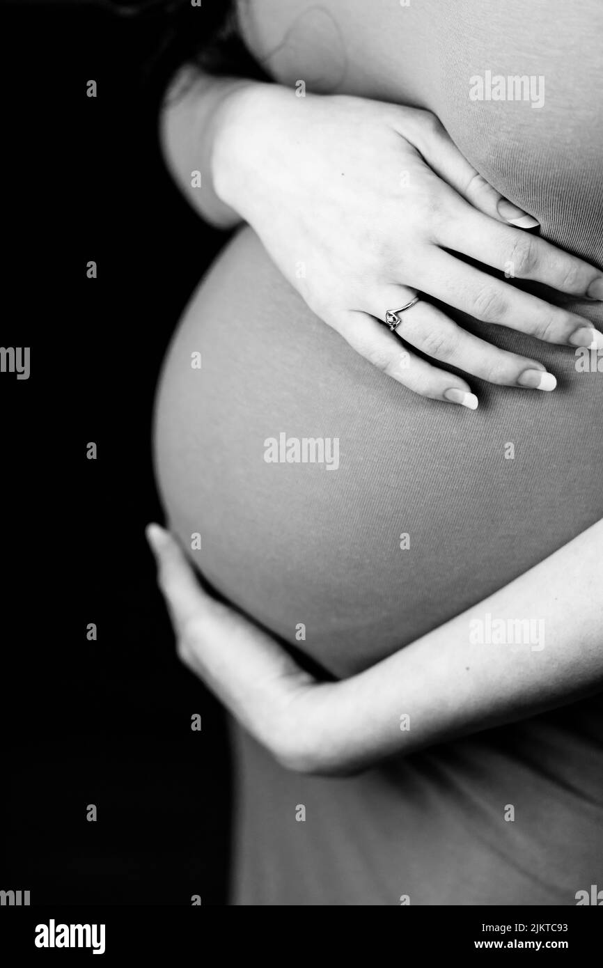 Donna incinta che tiene il suo ventre. 27 settimane Foto Stock