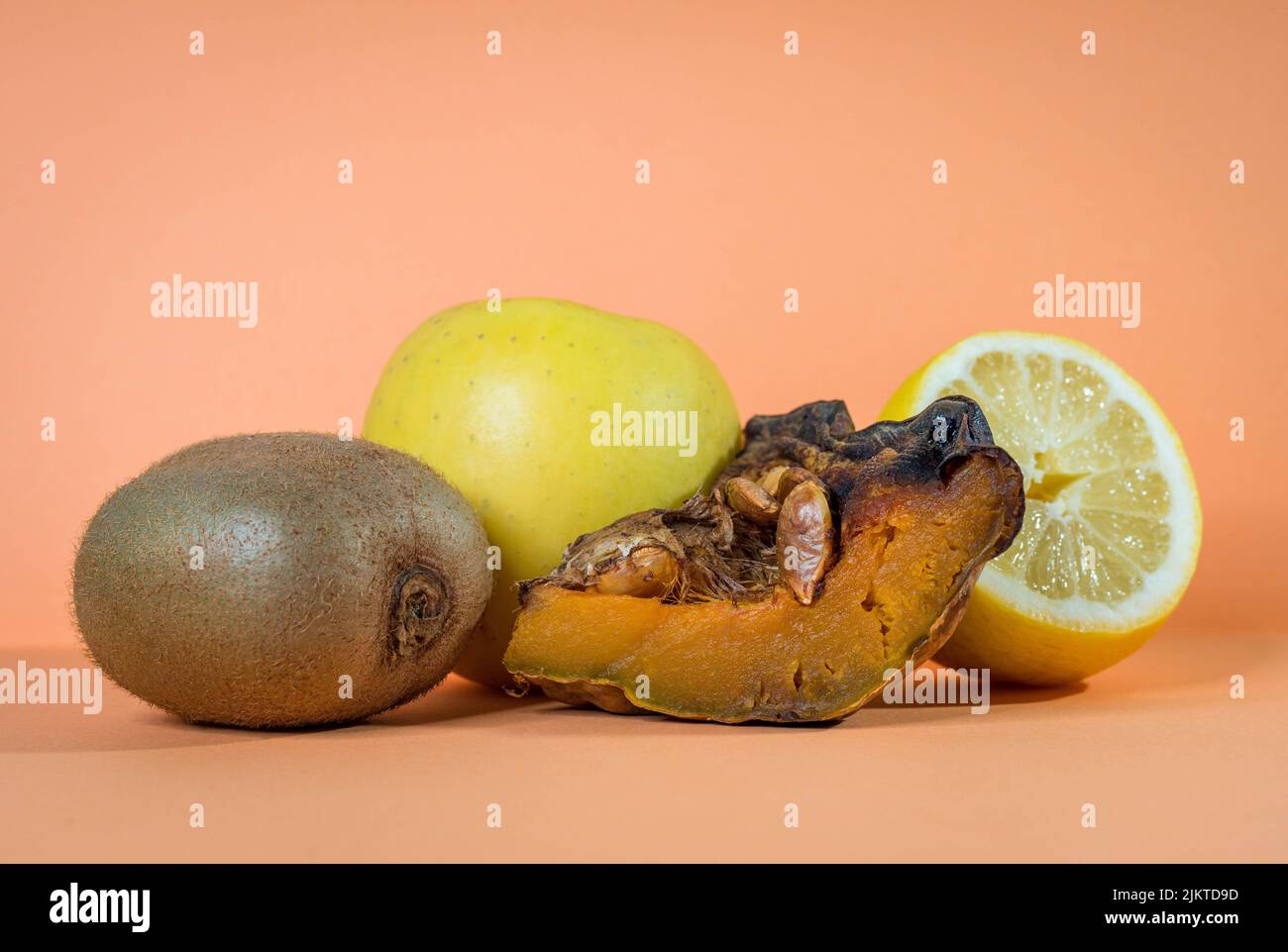 Immagine di isolato di frutta e limone delizioso, kiwi, mela e zucca al forno su uno sfondo arancione salmone rosa. Concetto di cibo sano. Foto Stock
