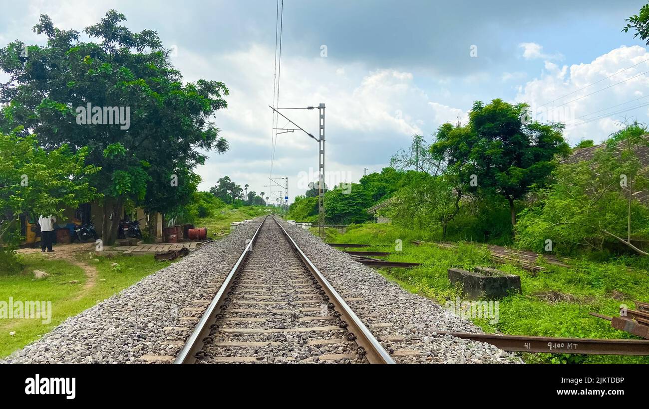 Un primo piano di ciottoli sulla ferrovia circondata dal verde in una giornata nuvolosa Foto Stock