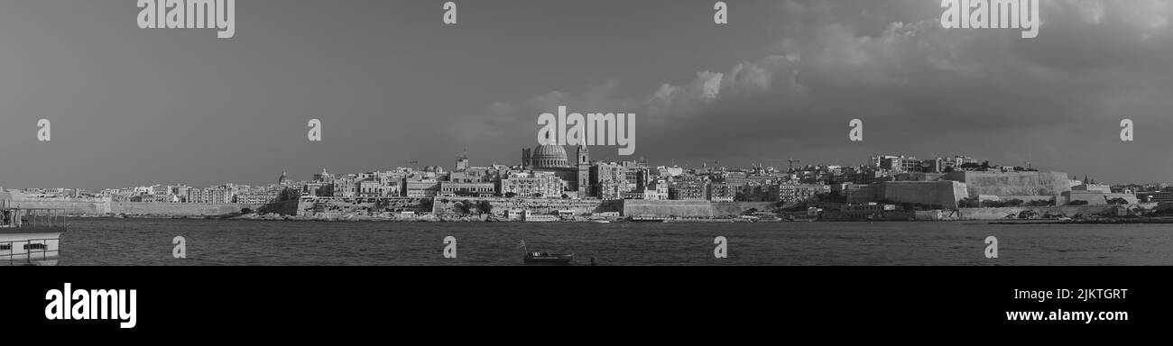 Una foto panoramica in scala di grigi di una città sulla spiaggia Foto Stock