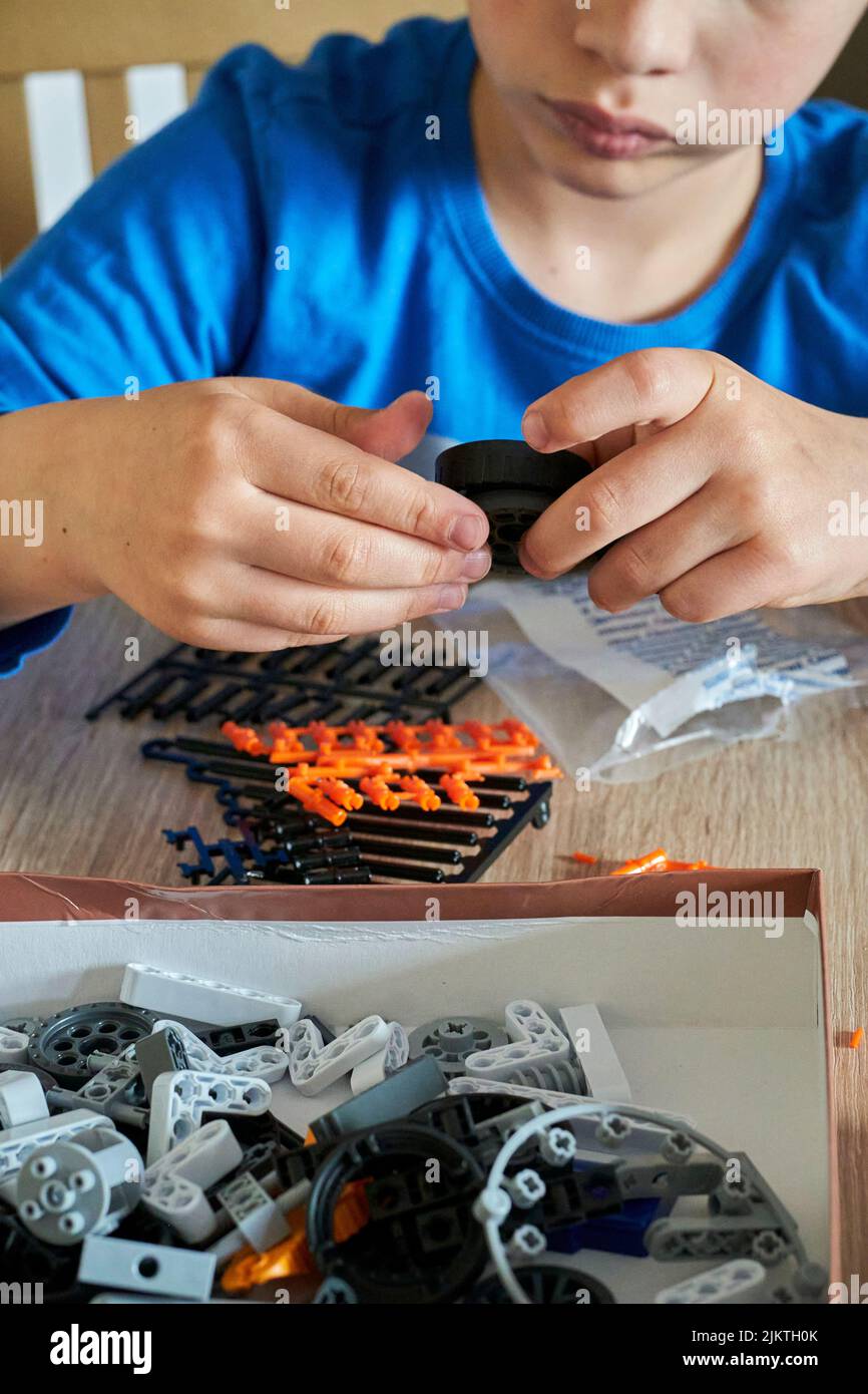 Un'immagine verticale di un bambino che costruisce un veicolo lunare da un edificio del marchio Celementoni su un tavolo di legno Foto Stock
