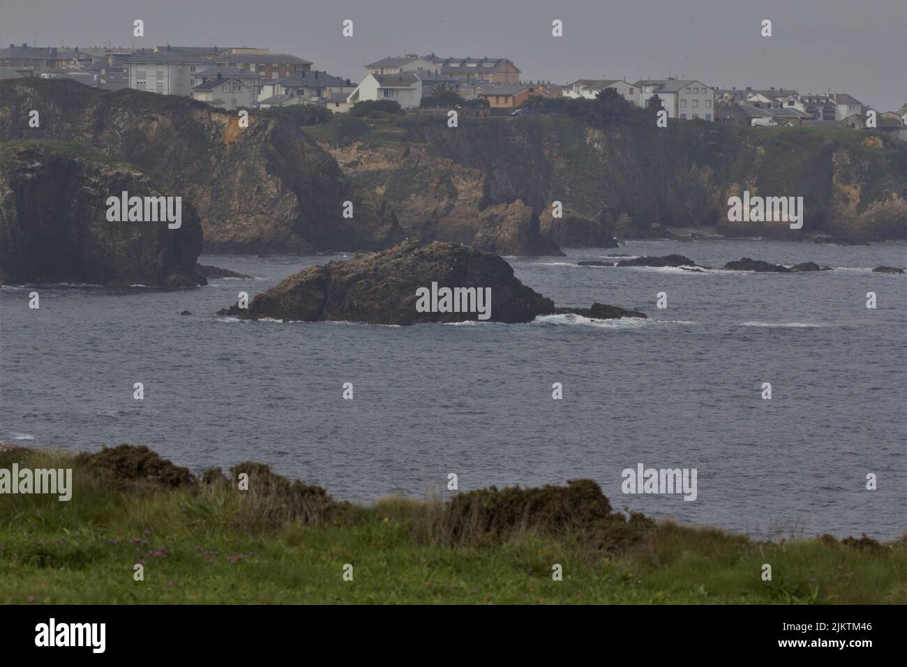 Una costa rocciosa con scogliere e onde calme durante il giorno Foto Stock