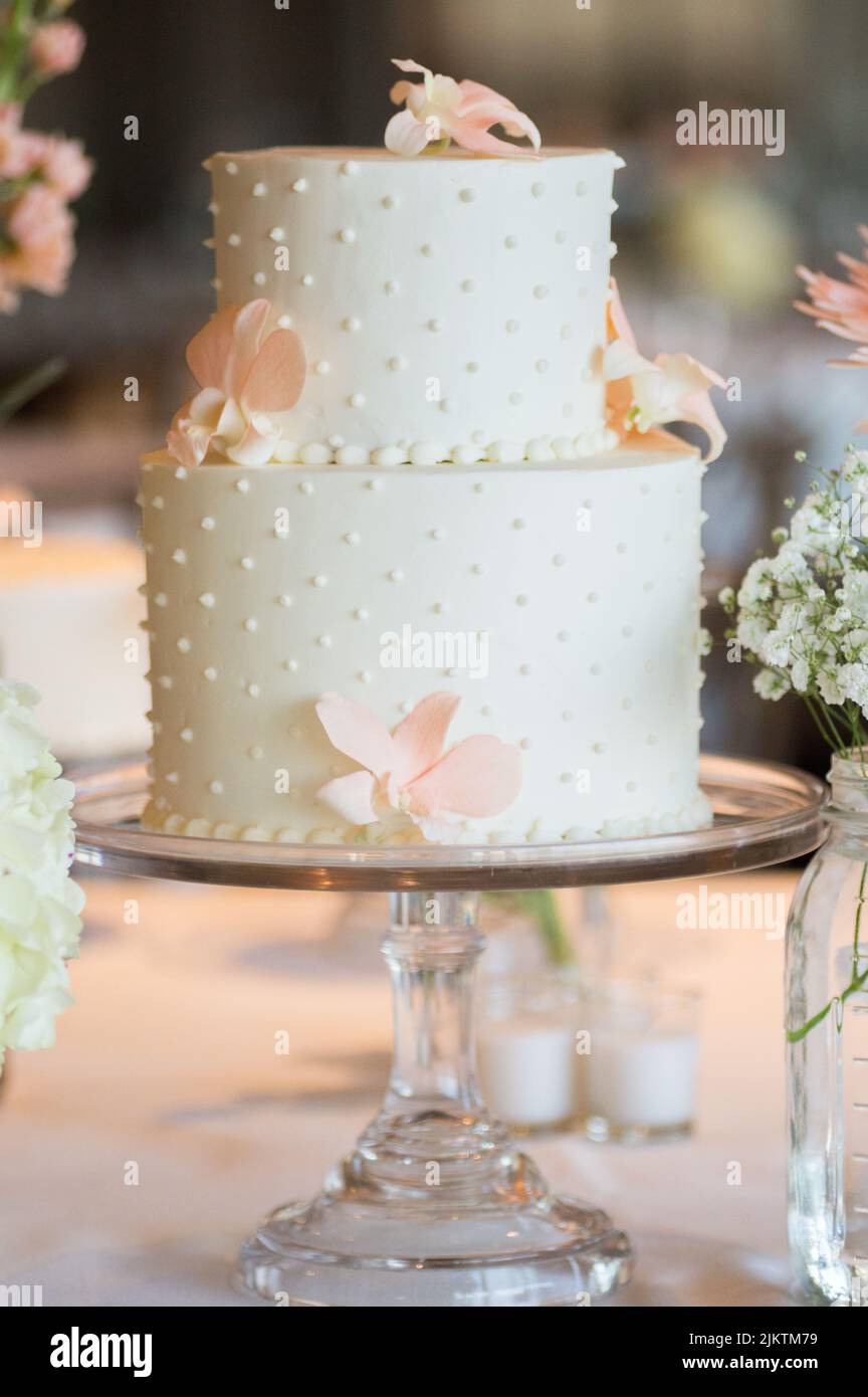Un primo piano verticale di una torta di nozze a due piani a pois di polka con fiori. Messa a fuoco superficiale. Foto Stock