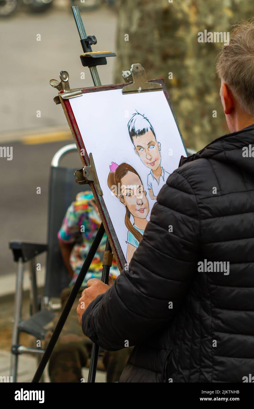 Barcellona, Spagna - 8 aprile 2022: Artista di strada che dipinge una caricatura sulla Rambla di Barcellona (Spagna), approccio selettivo al disegno. Foto Stock