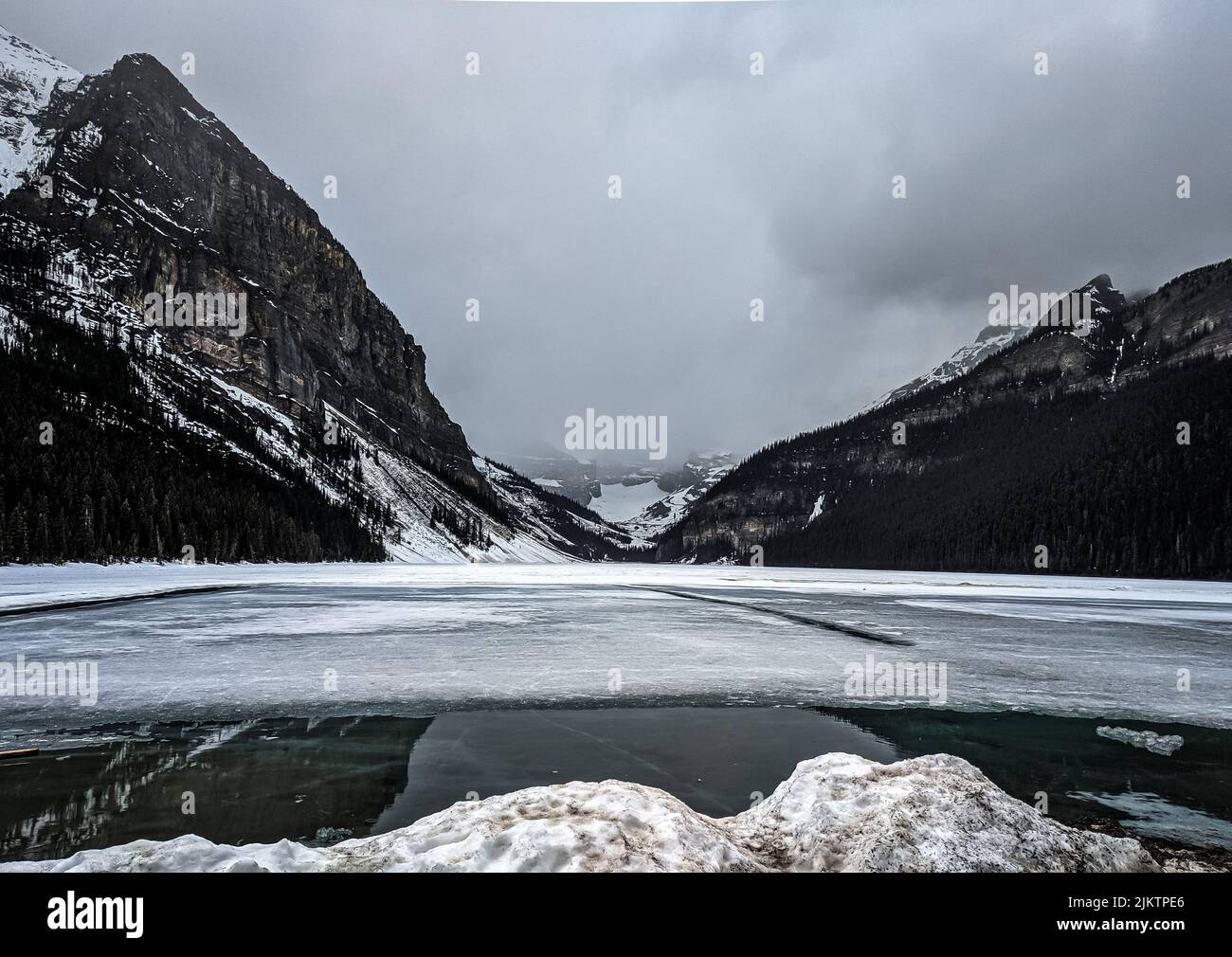 Un fiume che attraversa montagne innevate in una fredda e cupa giornata invernale Foto Stock
