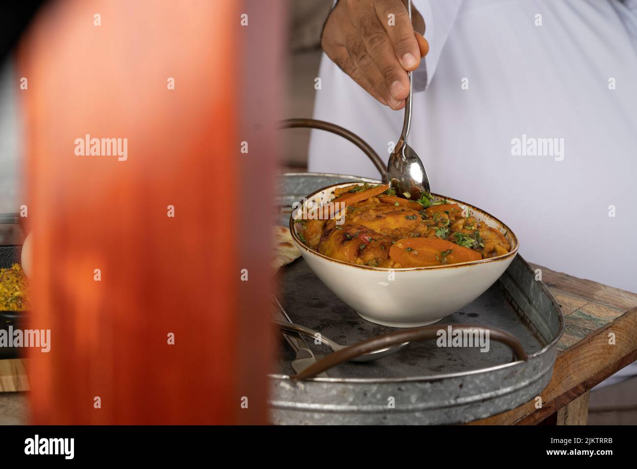 Un concentrato selettivo della mano di uno chef che mescola il pasto arabo con un cucchiaio Foto Stock