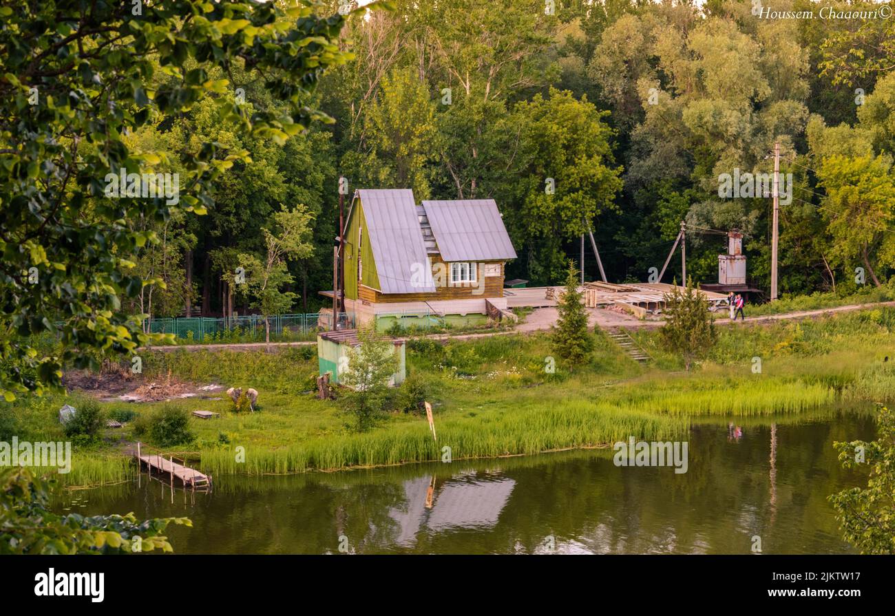 Una casa di villaggio sul lago in una campagna verde Foto Stock