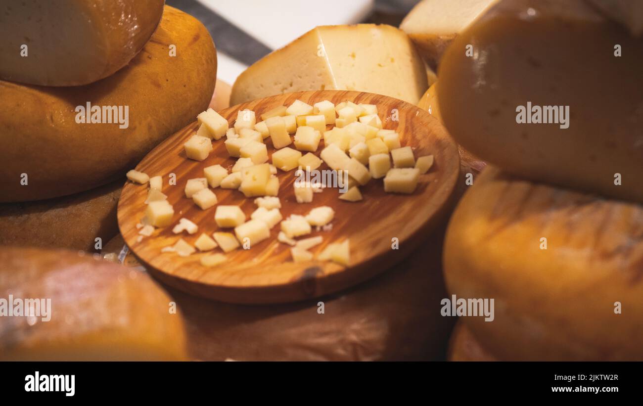 Tagliare i cubetti di formaggio su un asse di legno. Assortimento di deliziosi formaggi Foto Stock