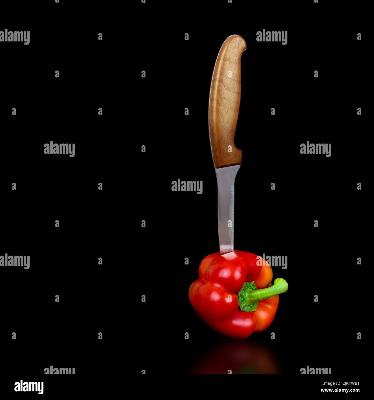 Pepe rosso con coltello da chef su sfondo nero Foto Stock