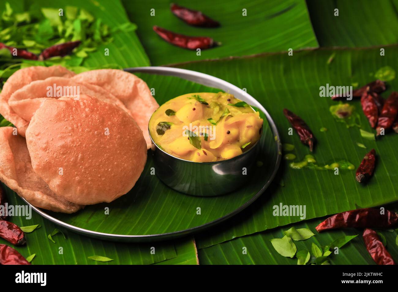 famosa colazione dell'india del sud poori o puri con curry di patate servito in un piatto con la foglia di banana closeup con fuoco selettivo e sfocatura Foto Stock