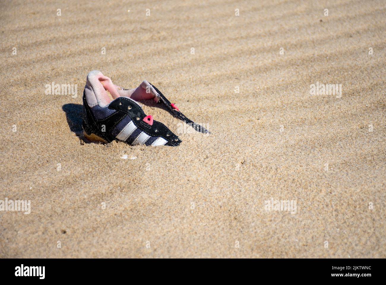Metà scarpa persa sepolta nella sabbia in spiaggia Foto Stock