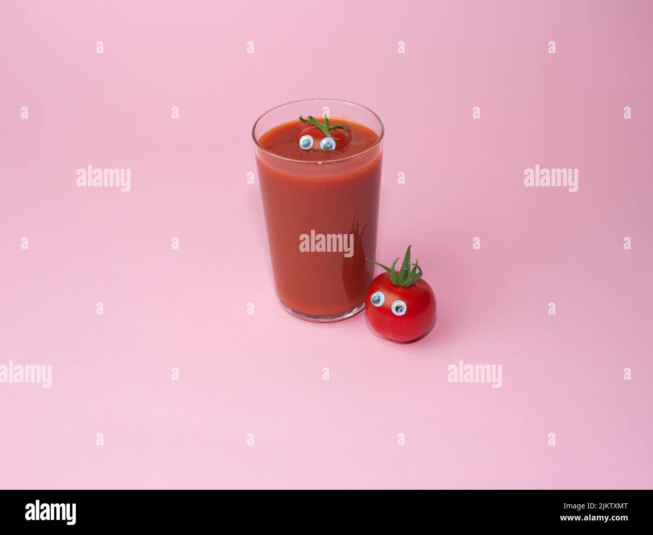 Un bicchiere di succo di pomodoro con pomodori ciliegini interi con occhi isolati su fondo rosa Foto Stock