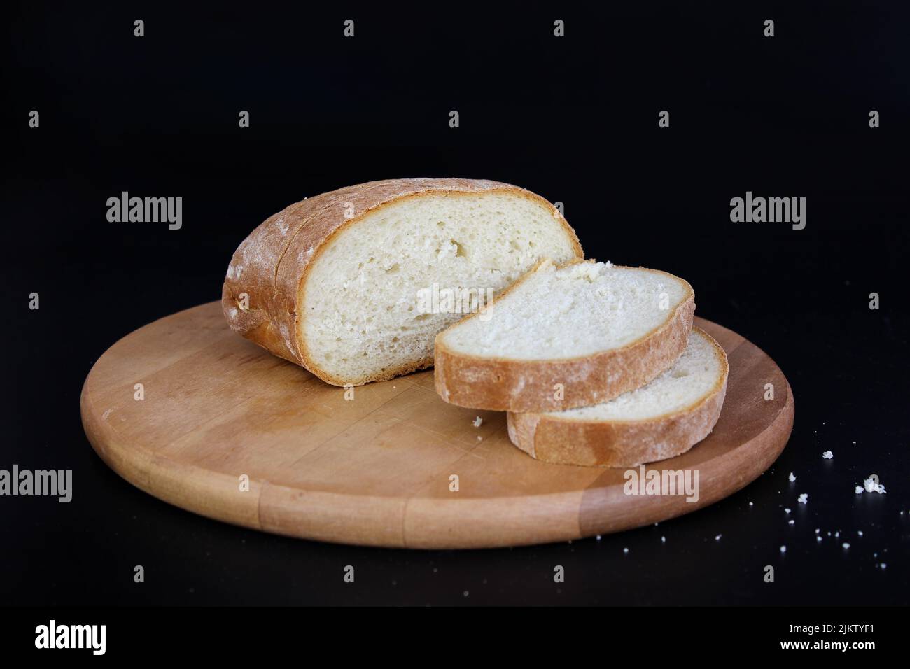 Pane appena sfornato, affettato con un coltello seghettato su un tagliere di legno. Foto Stock
