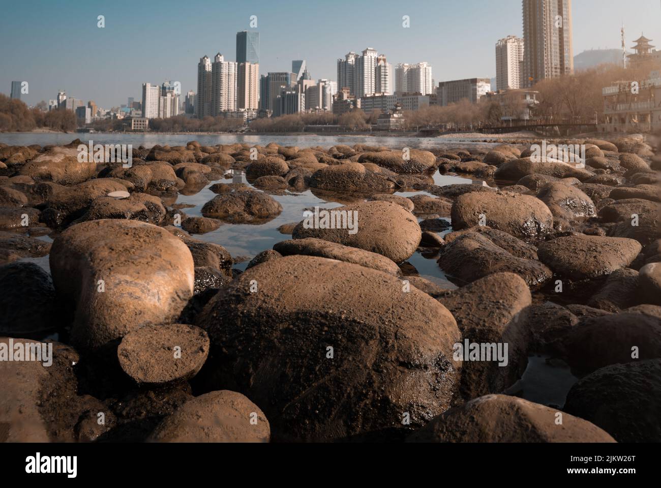 Un primo piano di grandi pietre sulla superficie dell'acqua sullo sfondo di una città con grattacieli Foto Stock