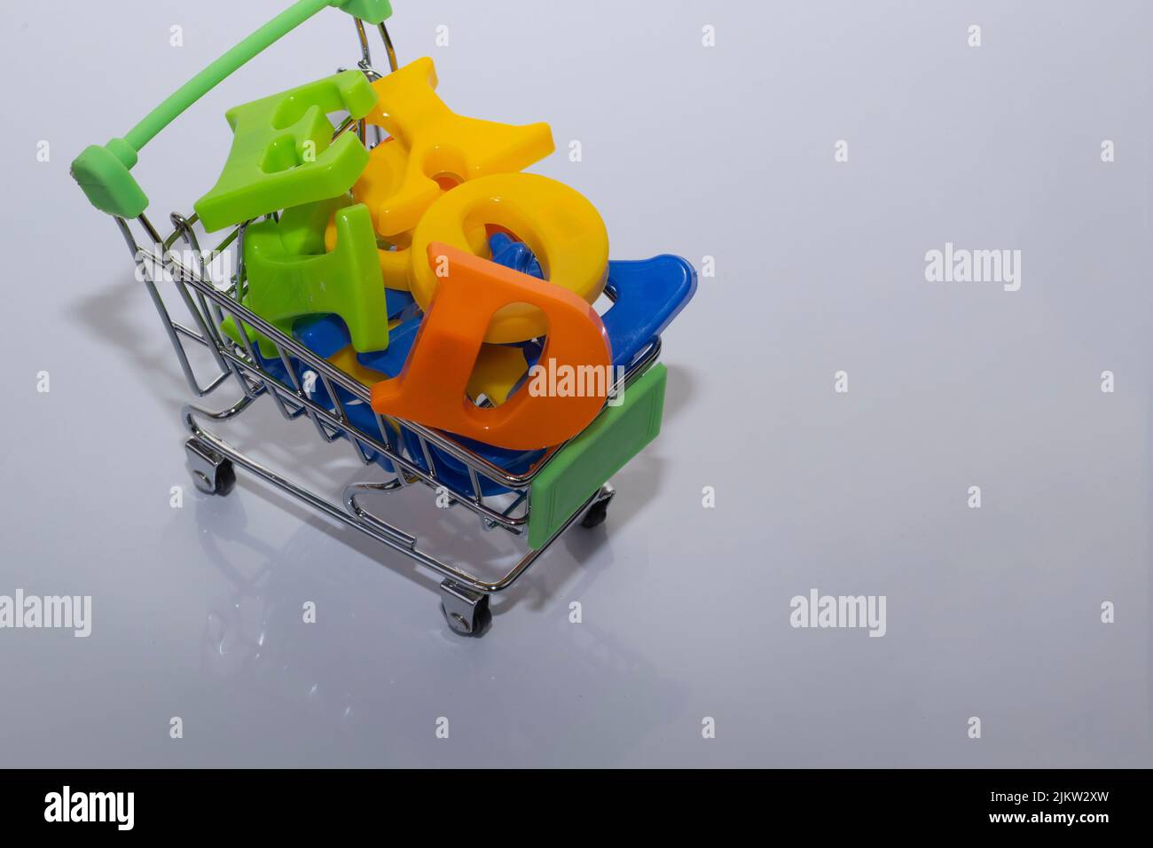 Shopping online lettere multicolore su sfondo primo piano, Carrello concetto immagine di un Alphabet Baby giocattolo - lettere, con sfondo bianco Copia Foto Stock