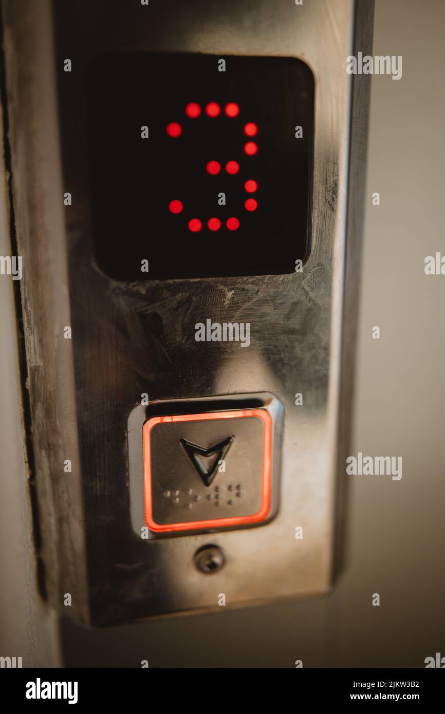 Un primo piano verticale di un pulsante dell'ascensore premuto che scende dal terzo piano Foto Stock
