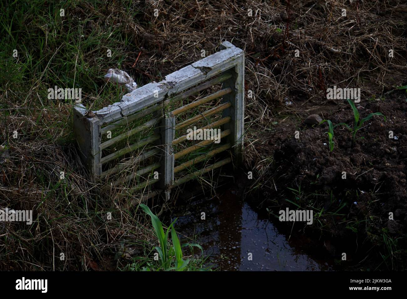 Un primo piano di un poster da giardino con acqua, fango ed erba Foto Stock