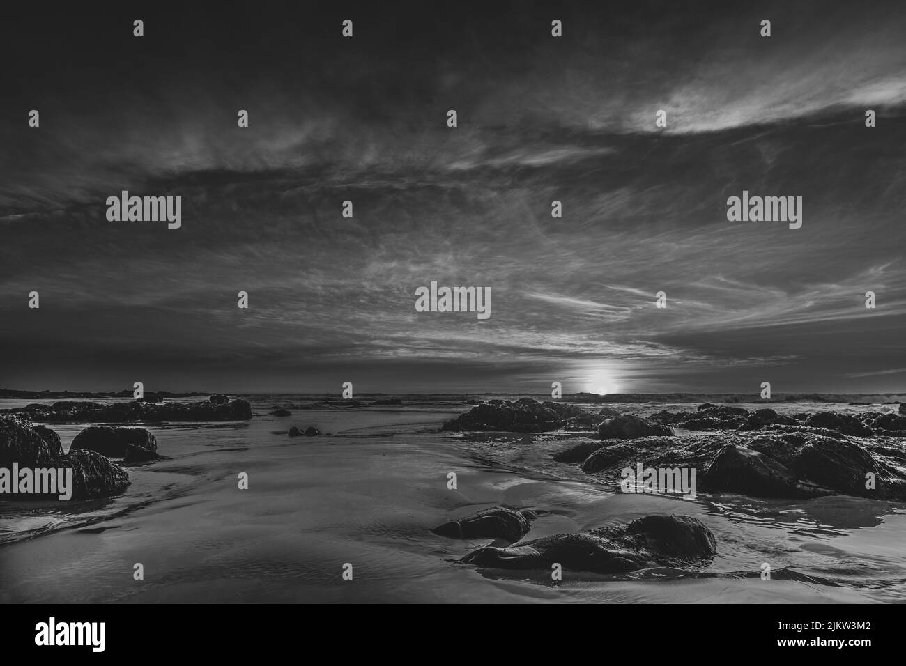 Una vista in scala di grigi del tramonto sul mare Foto Stock